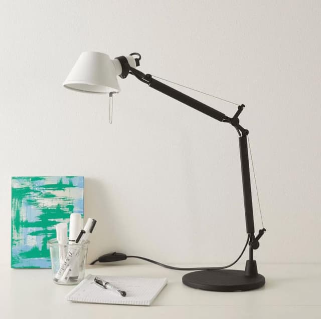 Lampe Artemide posée sur un bureau avec un carnet