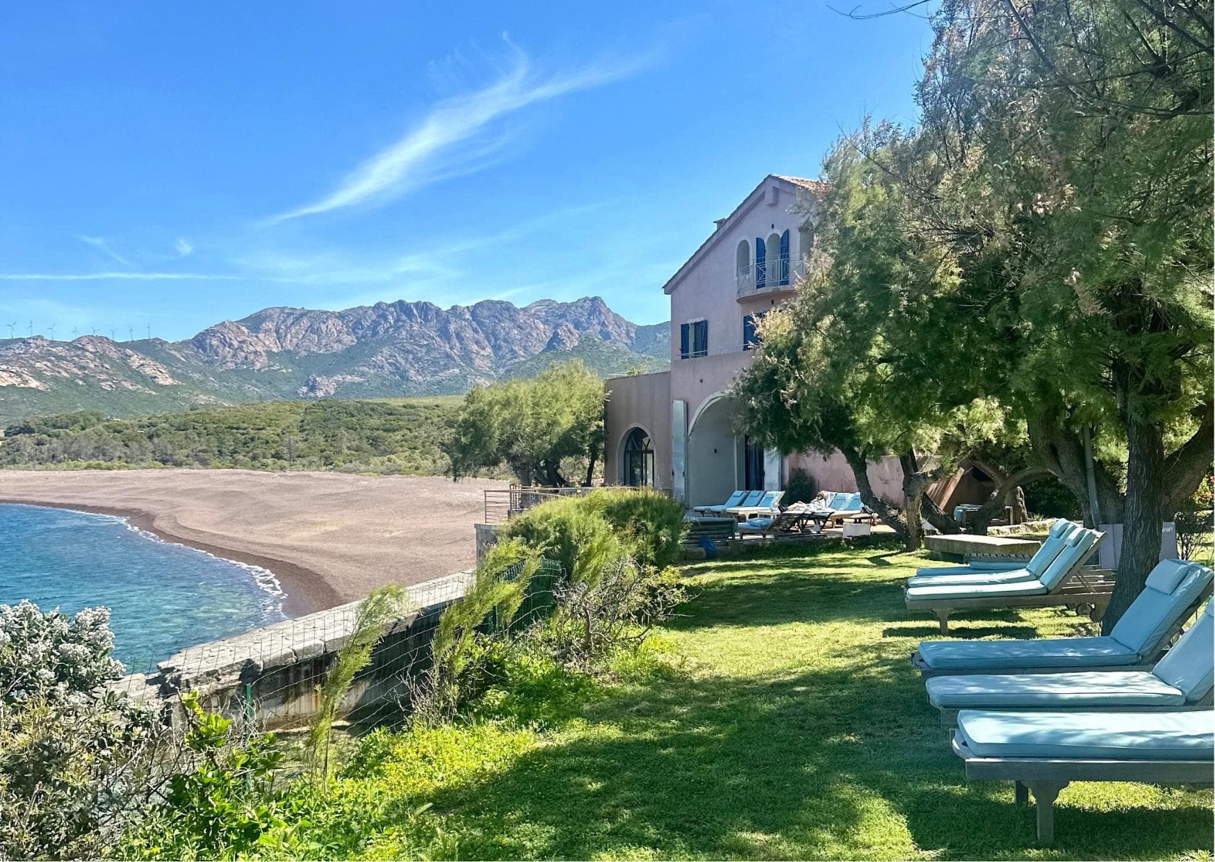 The deck chairs under the trees with a view of the sea and the mountains