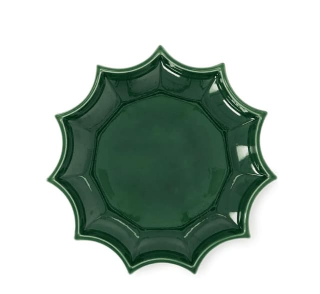 Une assiette en céramique vert foncé et brillante avec un bord festonné ressemblant à des pétales ou à une fleur, vue d'en haut.