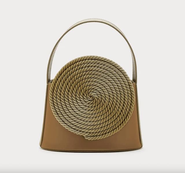 Un sac à main marron orné d'un motif unique en corde circulaire sur le devant. Doté d'une poignée unique et d'une forme structurée, il allie modernité et style artistique. Le motif en corde forme une spirale sur le devant.