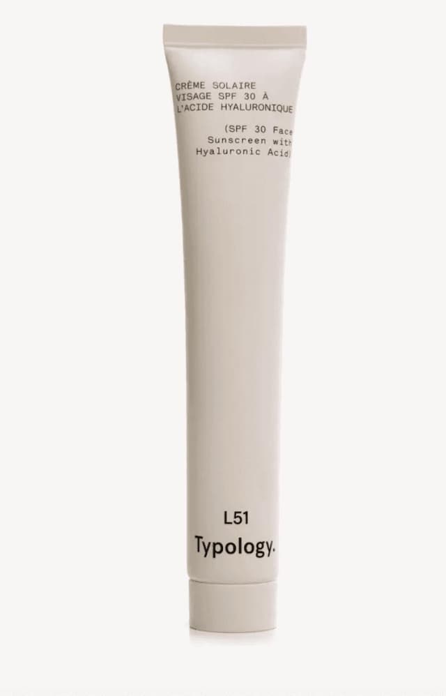 Un tube fin et beige portant les étiquettes « Crème Solaire Visage SPF 30 à l'Acide Hyaluronique » et « Typologie L51 ». Il s'agit d'une crème solaire visage à l'acide hyaluronique.