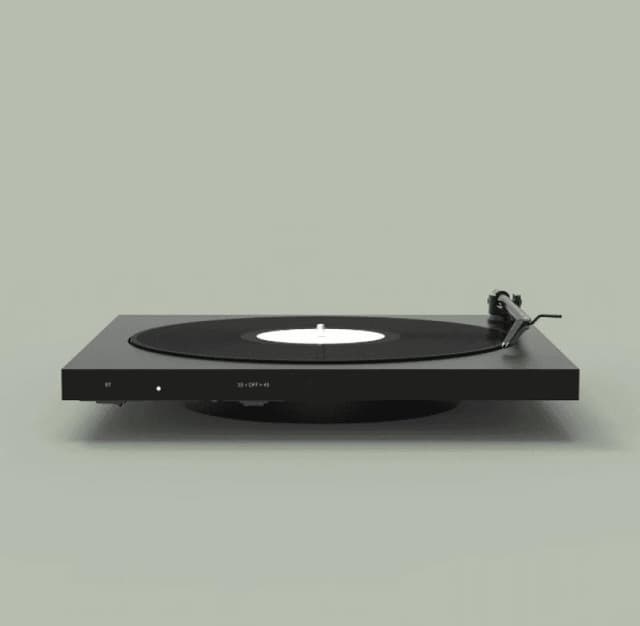 Une platine vinyle noire minimaliste repose sur un fond gris neutre, avec un disque vinyle noir et une étiquette blanche. Le bras de lecture est positionné sur le disque, prêt à lire la musique.