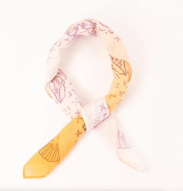 Un foulard en soie torsadé en boucle, orné d'un motif aux tons pastel crème, or et lavande. Ce modèle présente des motifs floraux et feuillus abstraits sur fond blanc.