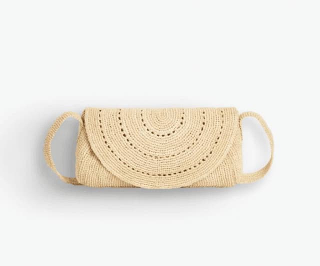 Petite pochette en paille tressée beige avec un rabat semi-circulaire et une fine bandoulière assortie, présentée sur un fond blanc.