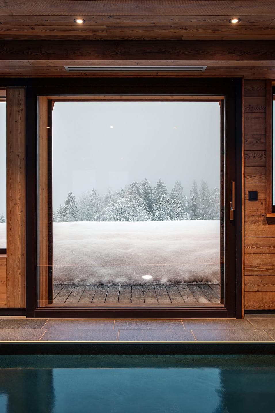Ultimate relaxation at Chalet Les Granges: dive into the heated indoor pool while enjoying views of the Alpine powder through the floor-to-ceiling windows.