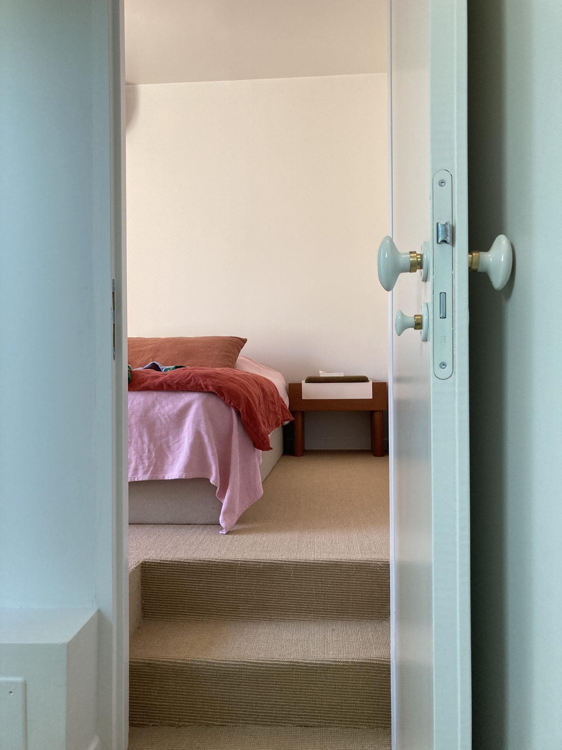 Une chambre-cocon et son sol en jonc de mer qui joue sur les codes déco des maisons de vacances.