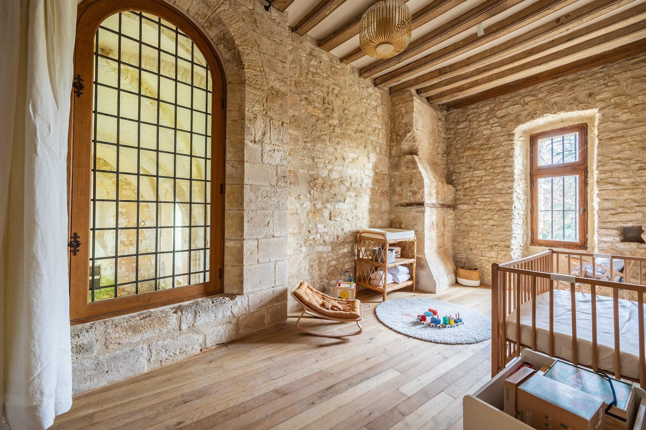 The children's bedroom, with its stone walls, exposed beams, and large windows overlooking the chapel and garden.