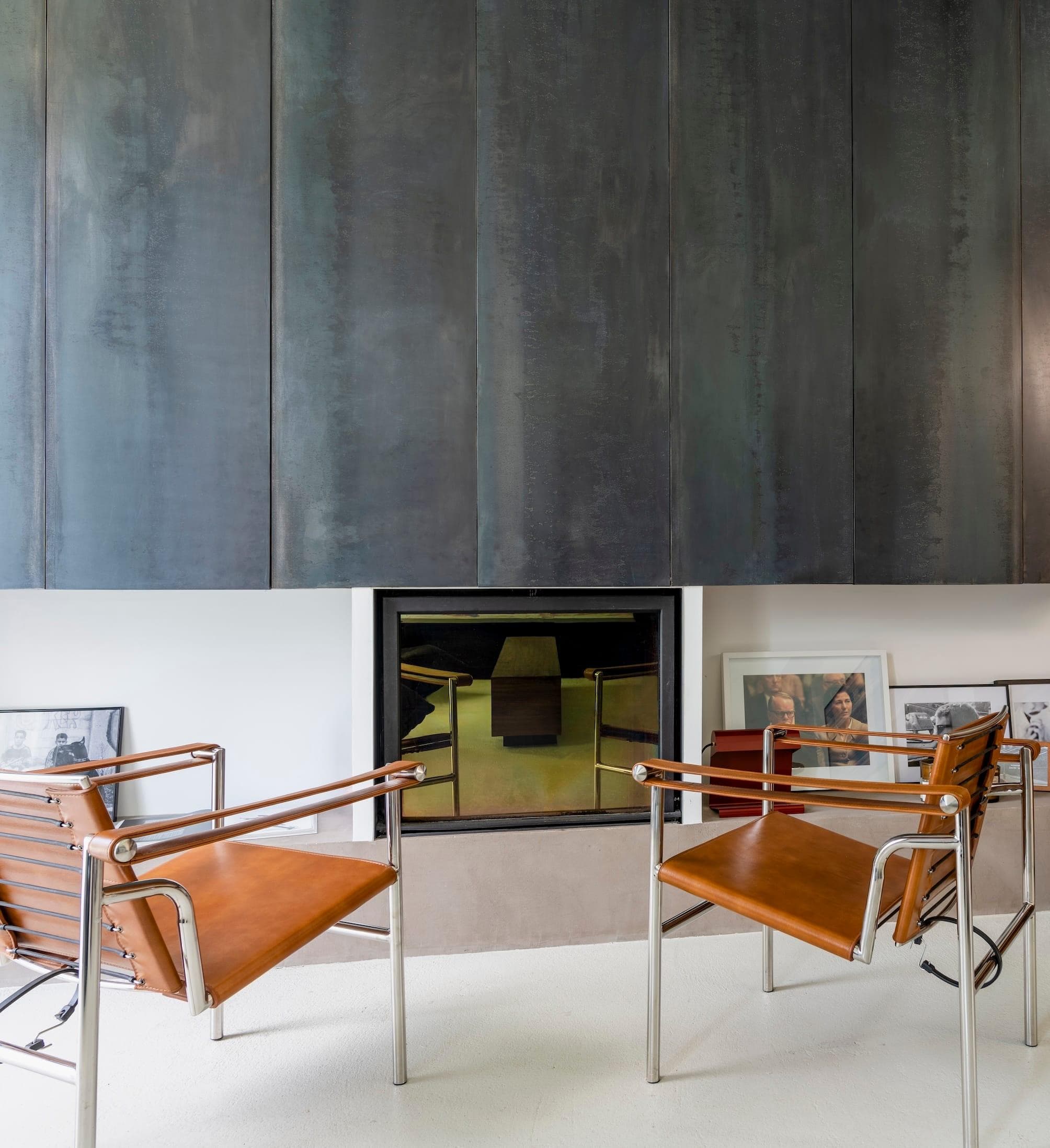 In the living room, an impressive metal wall surrounds the fireplace.