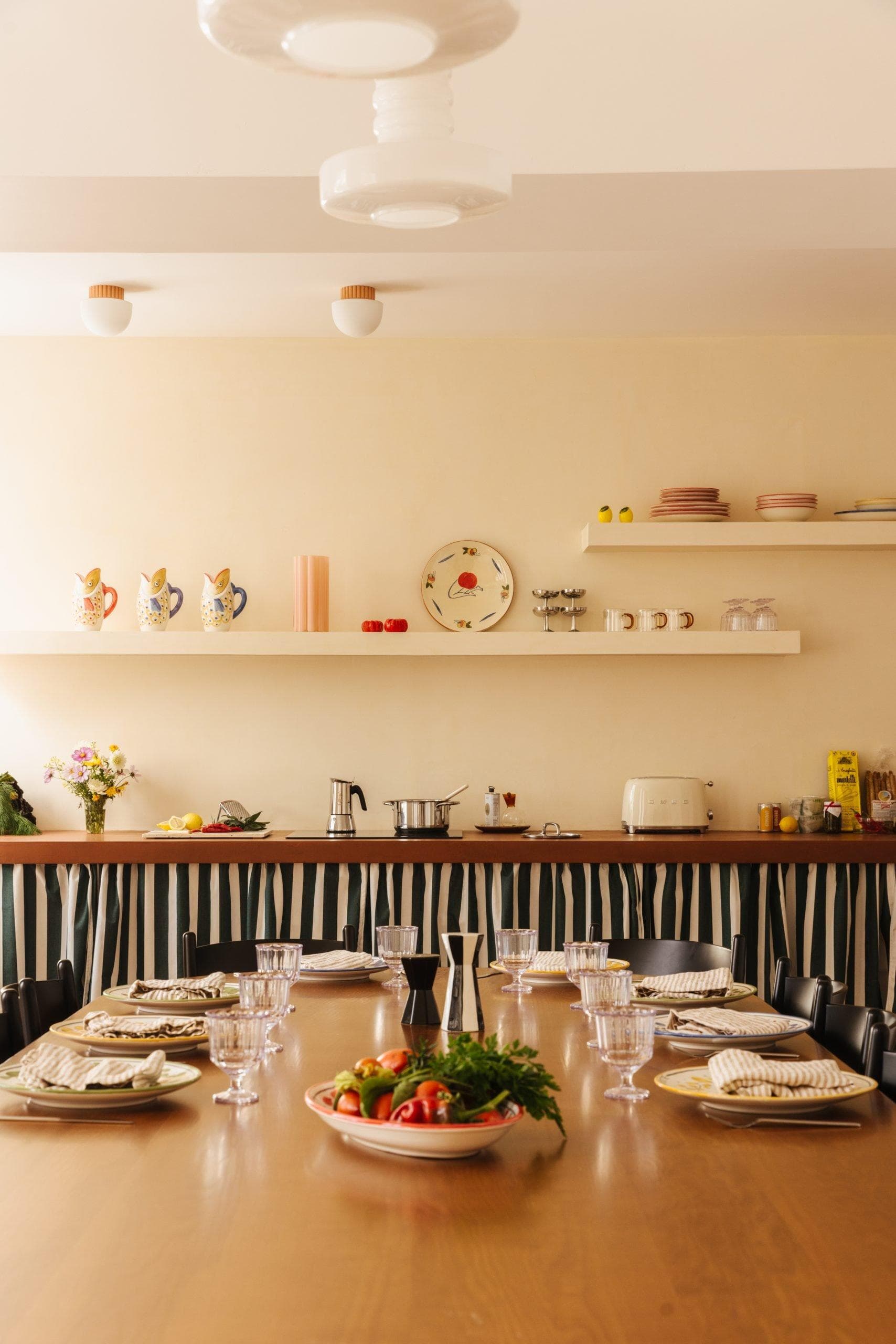 grande table en bois dressée, en arrière plan buffet et ustensiles de cuisine
